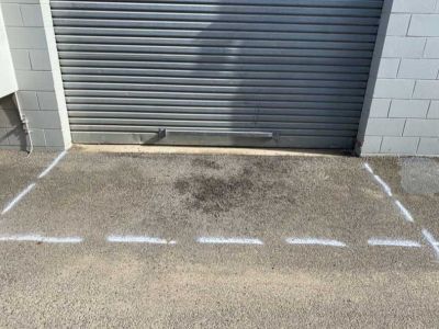 Roller door access area marked for asphalt patch repair with damaged pavement visible