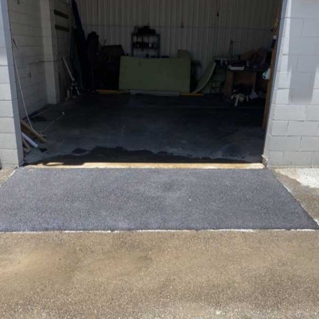 Completed asphalt patch repair at roller door access providing smooth entry surface