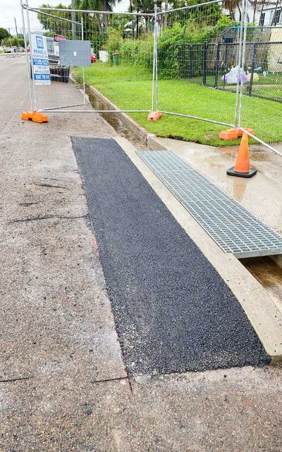 Asphalt patch repair completed around concrete drainage access for a smooth and durable road surface
