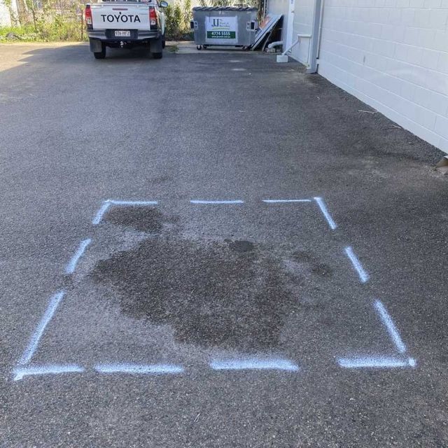 Commercial pavement marked out for asphalt patch repair with damaged surface visible