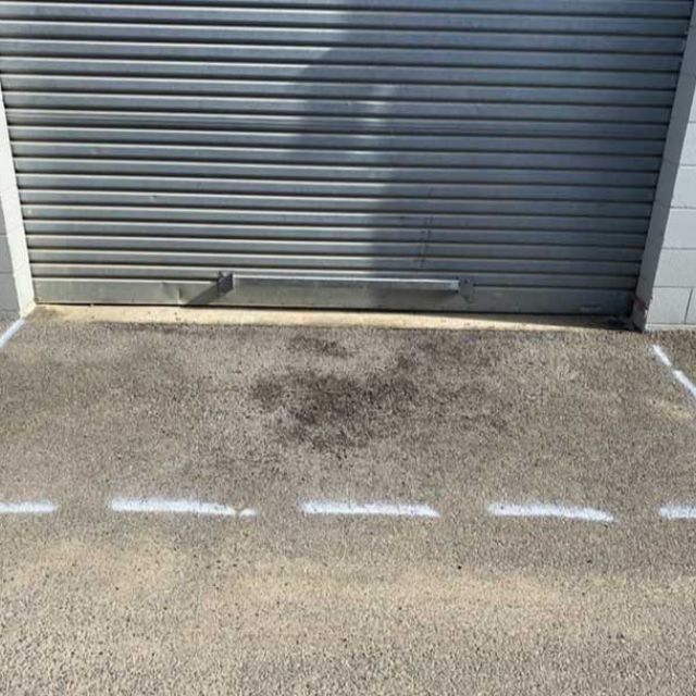 Roller door access area marked for asphalt patch repair with damaged pavement visible