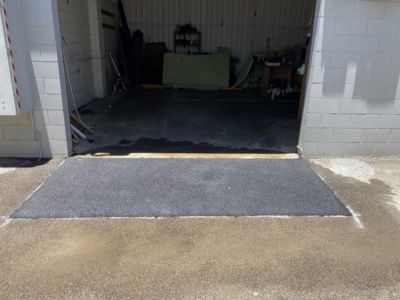 Completed asphalt patch repair at roller door access providing smooth entry surface